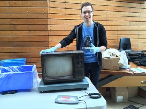 A student smiles and points to an old television set.