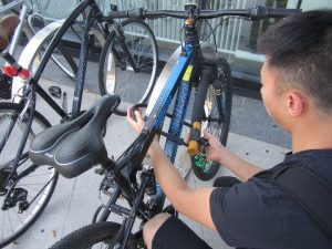 Photo of a man securing his bike using a bike lock. 