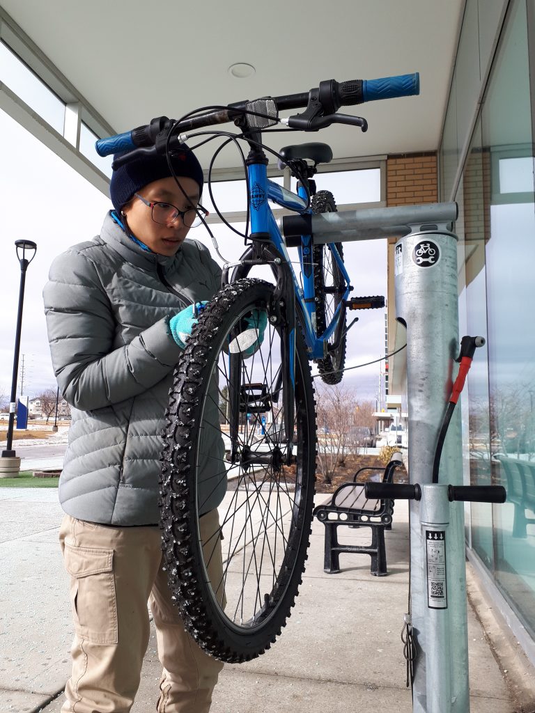A woman inspects her bike outside at the Davis free bike repair station.