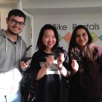 Three students standing together holding up their card holders and bracelet made with bike tubes.