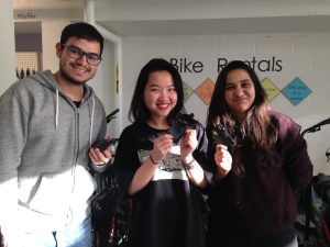 Three students standing together holding up their card holders and bracelet made with bike tubes.