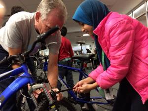 A repair cafe technician and a student focus on tuning up a bicycle.